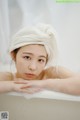 A woman with a towel wrapped around her head in a bathtub.