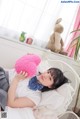 A woman laying on a bed holding a pink teddy bear.