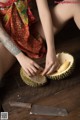 A woman sitting on a wooden table cutting a durian.