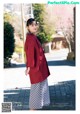 A woman in a red jacket and skirt standing on a sidewalk.