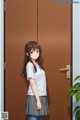 A girl standing in front of a brown door.