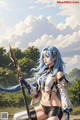 A woman with blue hair holding a sword in a field.