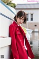 a woman in a red coat leaning against a boat