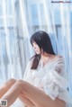 A woman in a white dress sitting on a window sill.