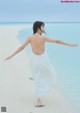 A woman in a white dress standing on a beach.