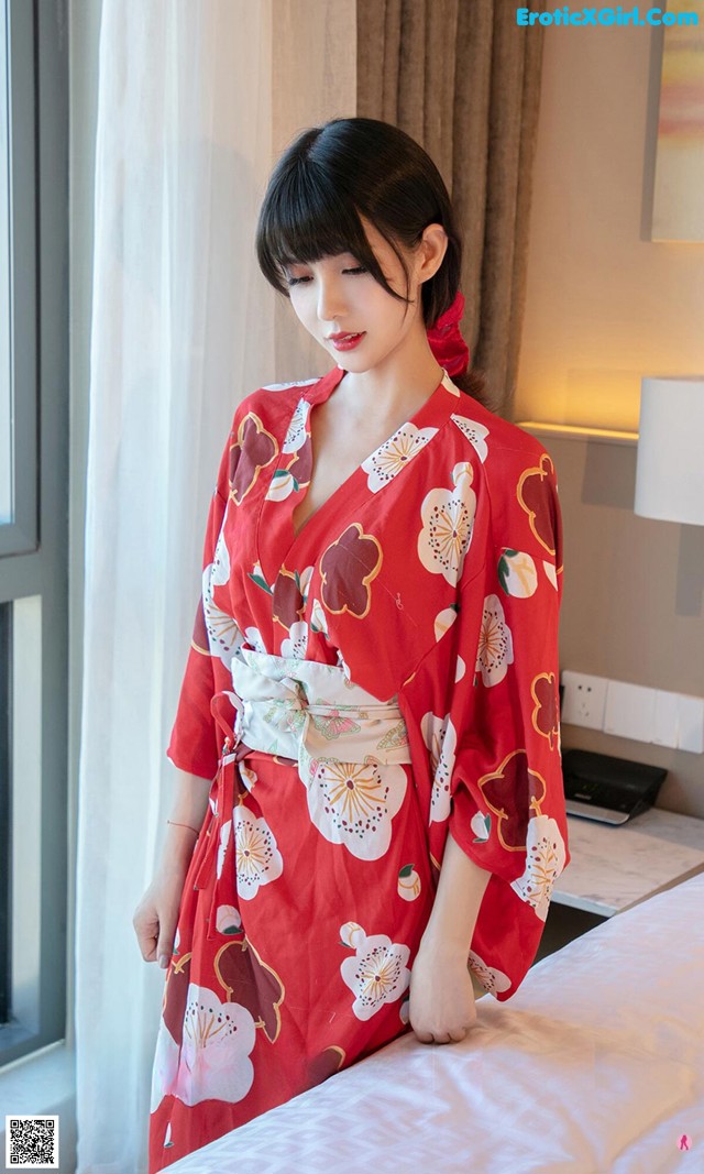 a woman in a red kimono standing on a bed