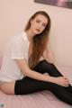 A woman sitting on top of a bed wearing black tights.