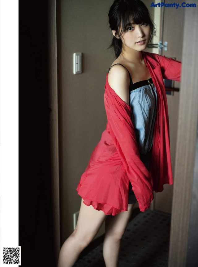 A woman in a red jacket and black shorts posing for a picture.