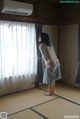 A woman standing in front of a window in a room.