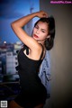 A woman in a black dress leaning against a wall.