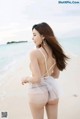 A woman in a white dress standing on a beach.