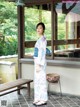 A woman in a kimono standing in front of a window.