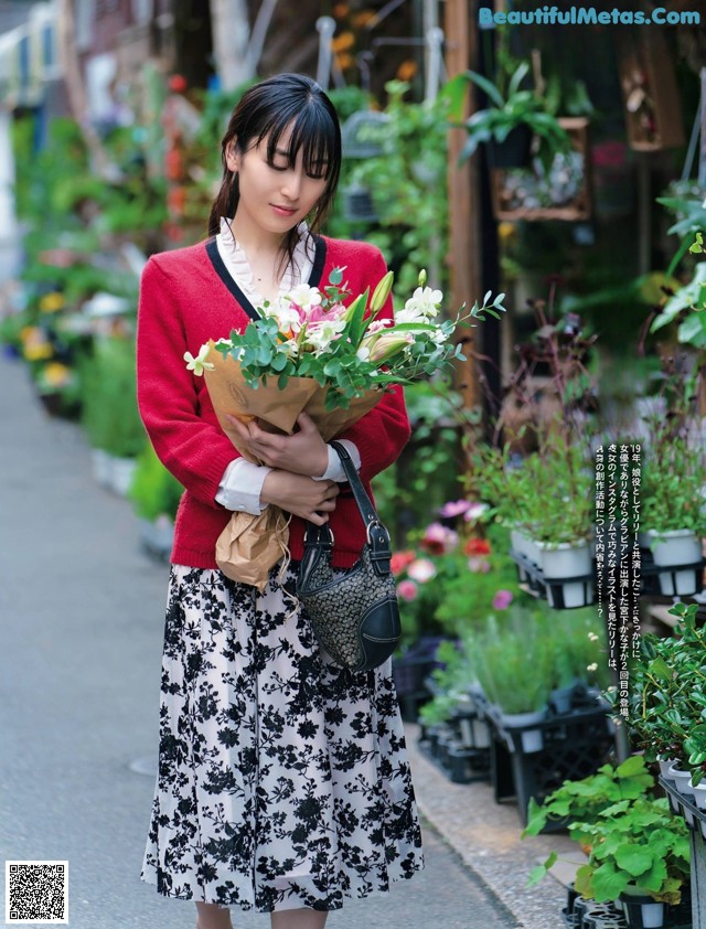 A woman walking down a street holding a bunch of flowers.