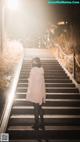 A woman in a pink coat is walking up some stairs.