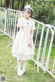 A woman in a white dress standing next to a white fence.